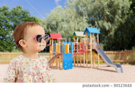 happy baby girl in sunglasses over playground 90523688