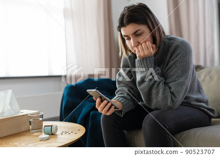 stressed woman with medicine and phone at home 90523707