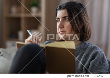 sad woman with diary sitting on sofa at home sad woman with diary sitting on sofa at home 90523709
