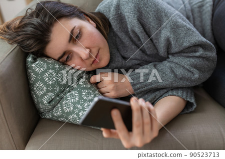 stressed woman with smartphone on sofa at home stressed woman with smartphone on sofa at home 90523713
