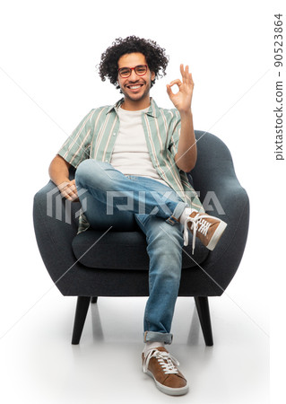 happy man sitting in chair and showing ok gesture happy man sitting in chair and showing ok gesture 90523864