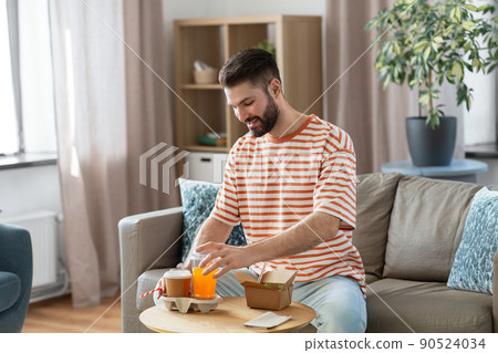 smiling man with takeaway food and drinks at home 90524034