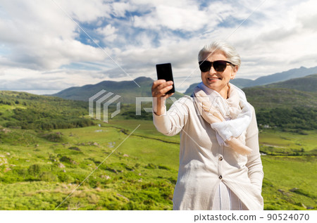 senior woman taking selfie by smartphone on beach 90524070