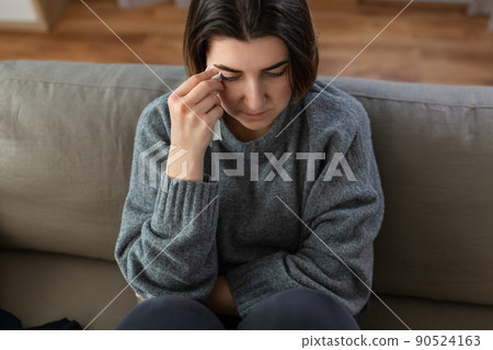 crying woman with tissue sitting on sofa at home crying woman with tissue sitting on sofa at home 90524163