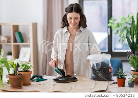 happy woman planting pot flowers at home happy woman planting pot flowers at home 90524238