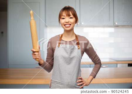 happy woman in apron with rolling pin in kitchen happy woman in apron with rolling pin in kitchen 90524245