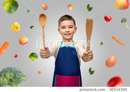 boy in apron with spoon and spatula over food 90524300