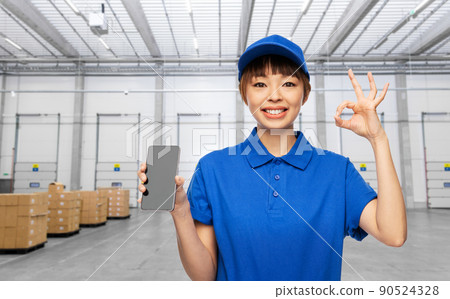 delivery woman with phone showing ok at warehouse delivery woman with phone showing ok at warehouse 90524328