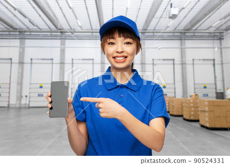 happy delivery woman with smartphone at warehouse 90524331