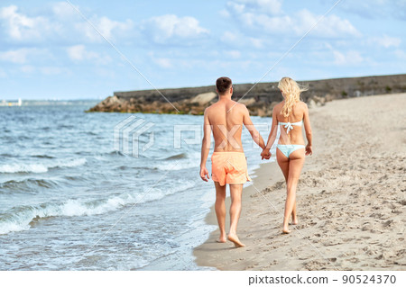 happy couple walking along summer beach 90524370