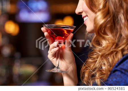 smiling woman drinking cocktail at night club smiling woman drinking cocktail at night club 90524381