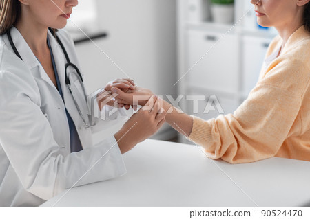 female doctor taking patient's pulse at clinic 90524470