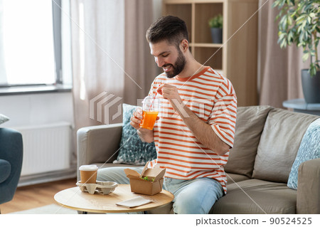 smiling man with takeaway food and drinks at home smiling man with takeaway food and drinks at home 90524525