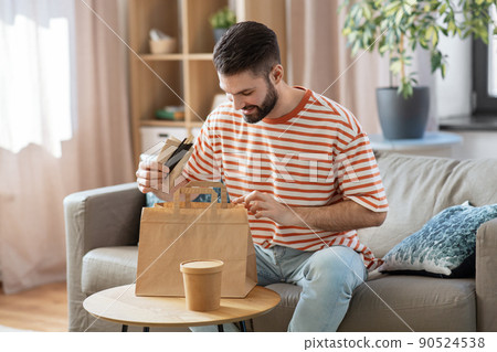 smiling man unpacking takeaway food at home 90524538