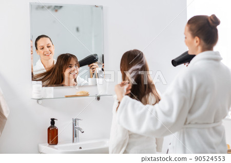 mother and daughter drying hair at bathroom mother and daughter drying hair at bathroom 90524553