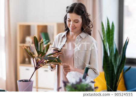 woman with smartphone and pot flower at home 90524555