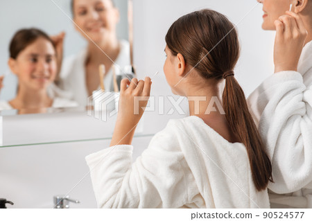 mother and daughter cleaning ears with cotton swab 90524577