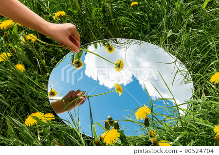 hand with dandelion and sky reflection in mirror 90524704