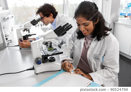 scientists with microscopes working in laboratory 90524799