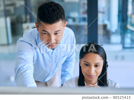 Passing the torch of customer service expertise. Shot of a young man helping his colleague in a modern call centre. Passing the torch of customer service expertise. Shot of a young man helping his colleague in a modern call centre. 90525415