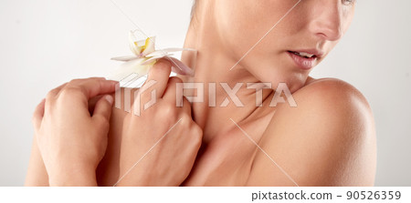 As perfect as a flower. Closeup studio shot of a beautiful young woman holding an orchid. As perfect as a flower. Closeup studio shot of a beautiful young woman holding an orchid. 90526359