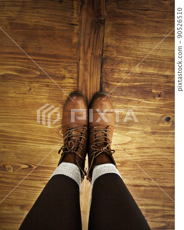 Rustic style. POV shot of a person wearing boots standing on a wooden floor. 90526510