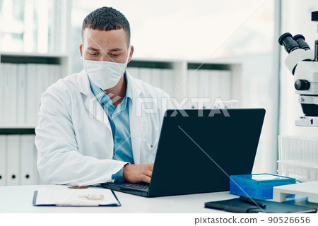 Not your average drug trial. Shot of a young scientist using a laptop while working on a coronavirus cure in a laboratory. 90526656