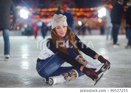 Im not sure how to stretch in skates..... Portrait of an attractive young woman sitting on an ice rink stretching her arms. Im not sure how to stretch in skates..... Portrait of an attractive young woman sitting on an ice rink stretching her arms. 90527255