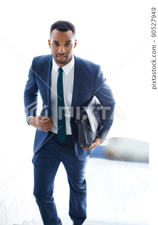 On his way to a meeting. A handsome african american businessman walking up the stairs while carrying a bag. 90527949