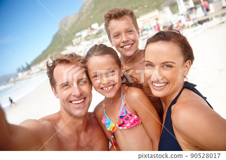 Say Beach. A happy family taking a selfie at the beach. 90528017