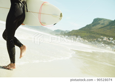 Going for it. A female surfer running into the ocean with her surfboard. Going for it. A female surfer running into the ocean with her surfboard. 90528074