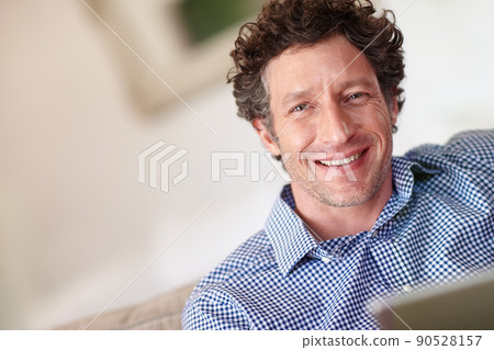 Enjoying the comforts of home. Cropped portrait of a happy man using his tablet at home. 90528157