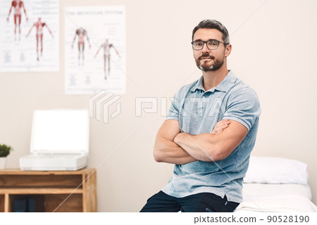 Helping you heal is my job. Portrait of a handsome mature male physiotherapist posing with his arms folded in his office. Helping you heal is my job. Portrait of a handsome mature male physiotherapist posing with his arms folded in his office. 90528190