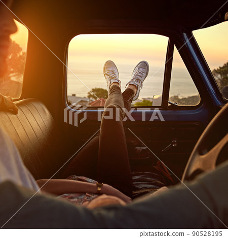 Take a break, you deserve it. Shot of a young woman relaxing on her boyfriends lap with her feet up during a road trip. 90528195