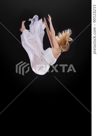 Dreams are illustrations from the book of your psyche. Studio shot of a woman falling upside down against a black background. 90528255