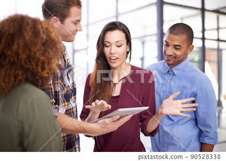 Technology and teamwork are all the resources they need. Cropped shot of a team of designers working together on a digital tablet in an office. 90528338