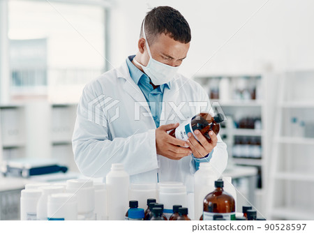 Unmasking the virus. Shot of a young scientist analysing medication in a laboratory. Unmasking the virus. Shot of a young scientist analysing medication in a laboratory. 90528597