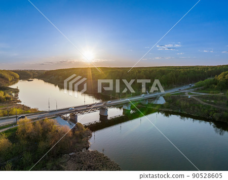 Beautiful view of the bridge across the Iset river in the city of Kamensk-Uralsky at sunset in spring. Kamensk-Uralskiy, Sverdlovsk region, Ural mountains, Russia. 90528605