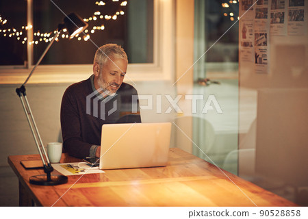 Hes never one to shy away from work. Cropped shot of a mature businessman working late at the office. Hes never one to shy away from work. Cropped shot of a mature businessman working late at the office. 90528858
