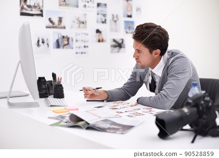 Making his final selection. A photographer looking at his images in his office. Making his final selection. A photographer looking at his images in his office. 90528859