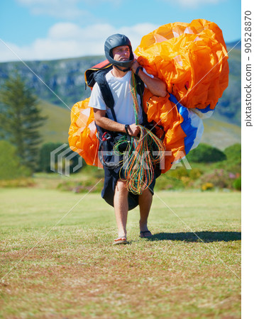 Ready for action. Shot of a man carrying his paragliding equipment. 90528870