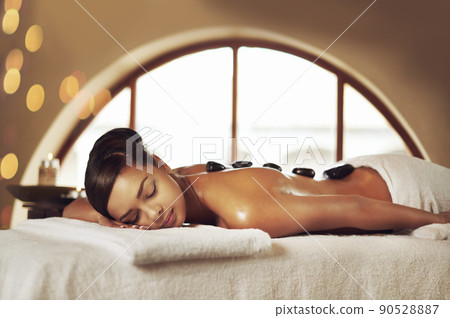 Total stress relief. Cropped shot of a young woman enjoying some lastone therapy at the spa. Total stress relief. Cropped shot of a young woman enjoying some lastone therapy at the spa. 90528887