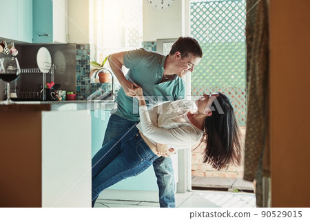 He still knocks me off my feet. Shot of a loving young couple dancing in the kitchen. 90529015