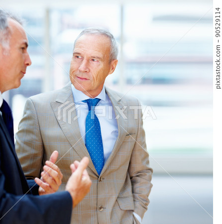 Two senior executives conversing. Two senior business men having discussion indoors. Two senior executives conversing. Two senior business men having discussion indoors. 90529114