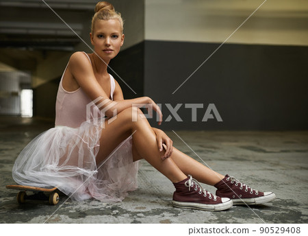 Swapping slippers for sneakers. A beautiful ballerina sitting on a skateboard wearing sneakers. Swapping slippers for sneakers. A beautiful ballerina sitting on a skateboard wearing sneakers. 90529408