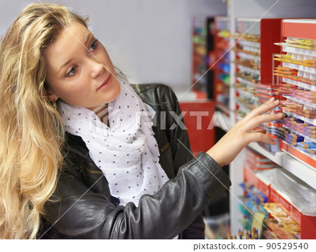 Stocking up her art kit. Shot of a young female artist looking at a variety of pencils or chalk in an art store. 90529540