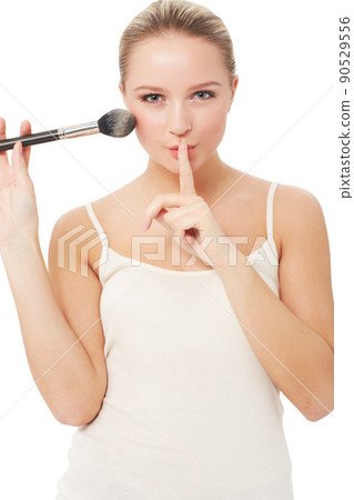 These are my beauty secrets.... A pretty woman putting a finger to her lips while applying blush to her face. These are my beauty secrets.... A pretty woman putting a finger to her lips while applying blush to her face. 90529556