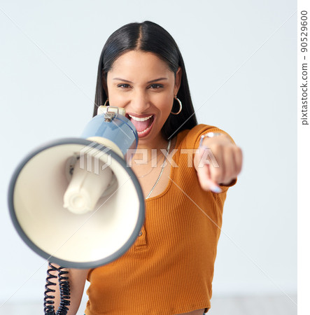 We need your support. Cropped portrait of an attractive young woman shouting into a megaphone and pointing at the camera in studio. 90529600