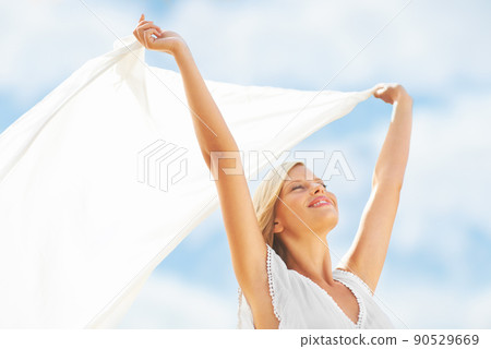 Feeling alive with vital energy. A beautiful young woman holding a scarf in the breeze. Feeling alive with vital energy. A beautiful young woman holding a scarf in the breeze. 90529669