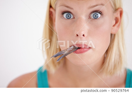 The taste of this fish is surprising. Portrait of a young woman eating a whole fish. 90529764